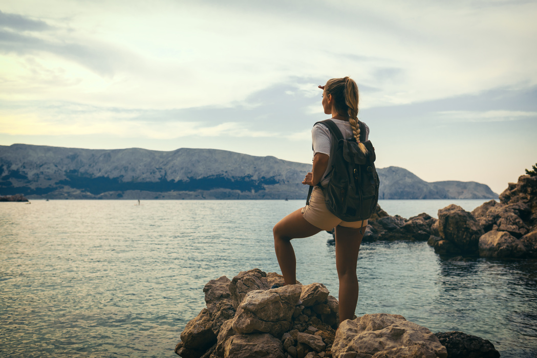 Female Backpacker Standing on a Rock on the Seashore